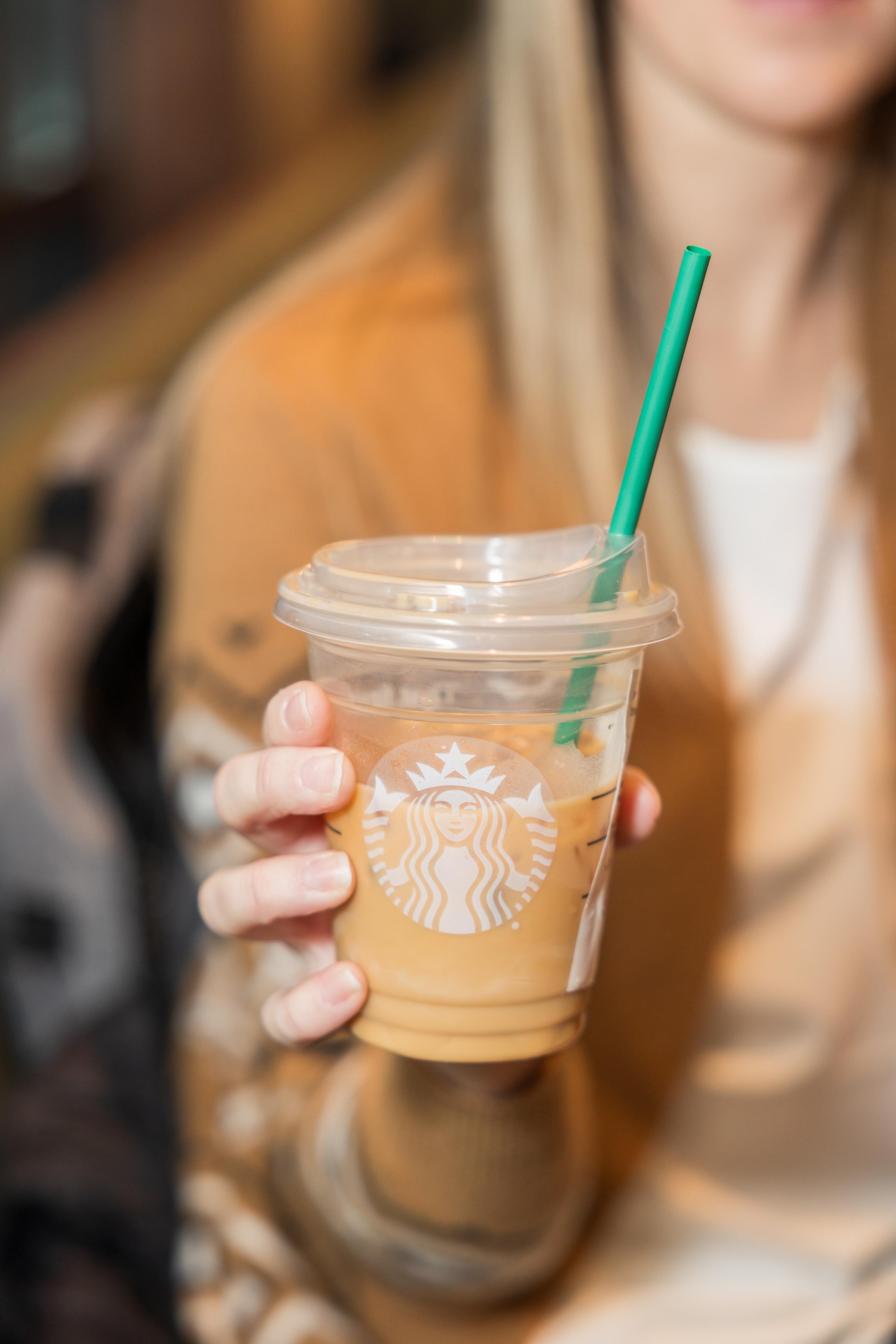 Women holding up a cup of iced coffee at Starbucks 