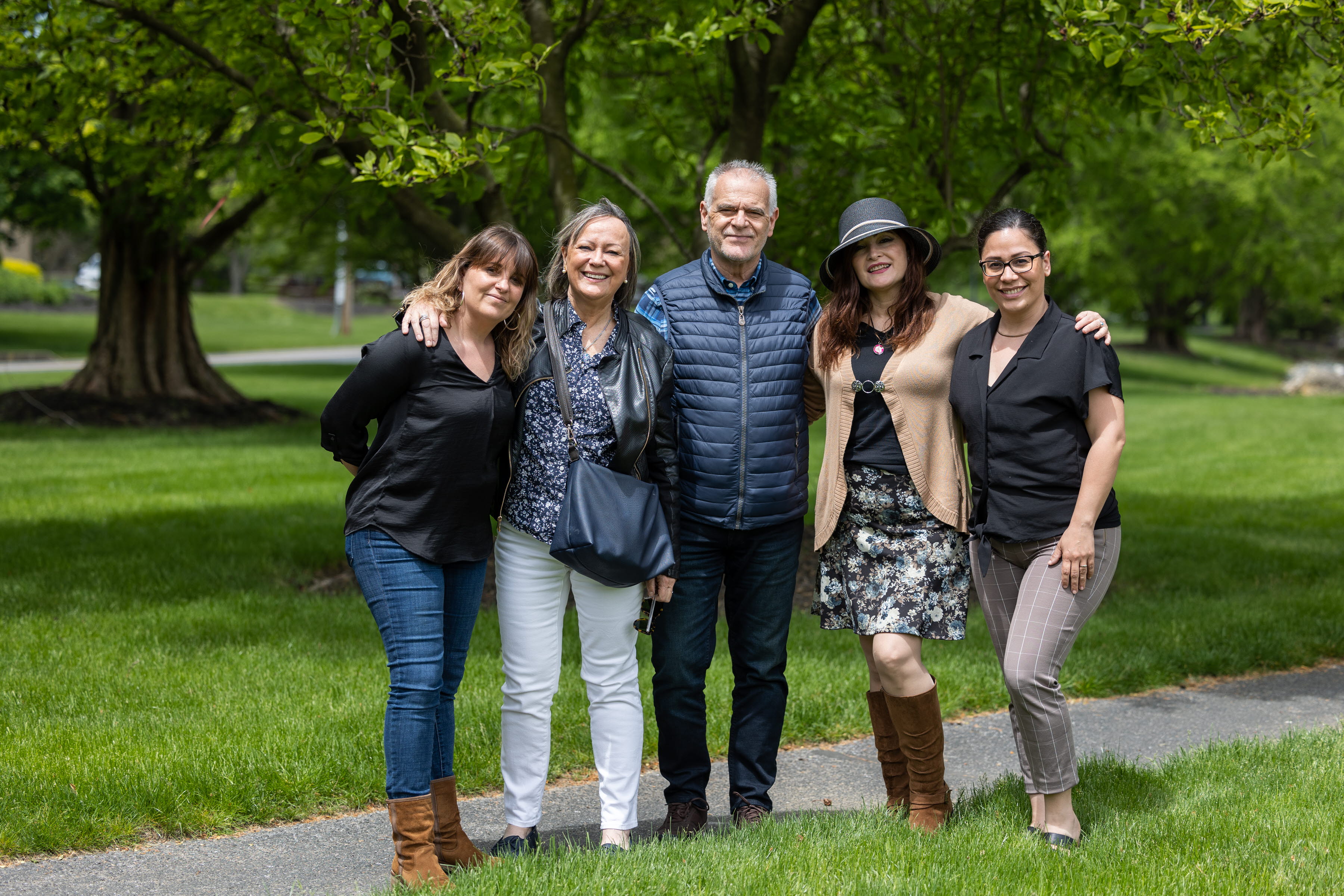 Four adult woman and one adult male posing for photo outside in park. 
