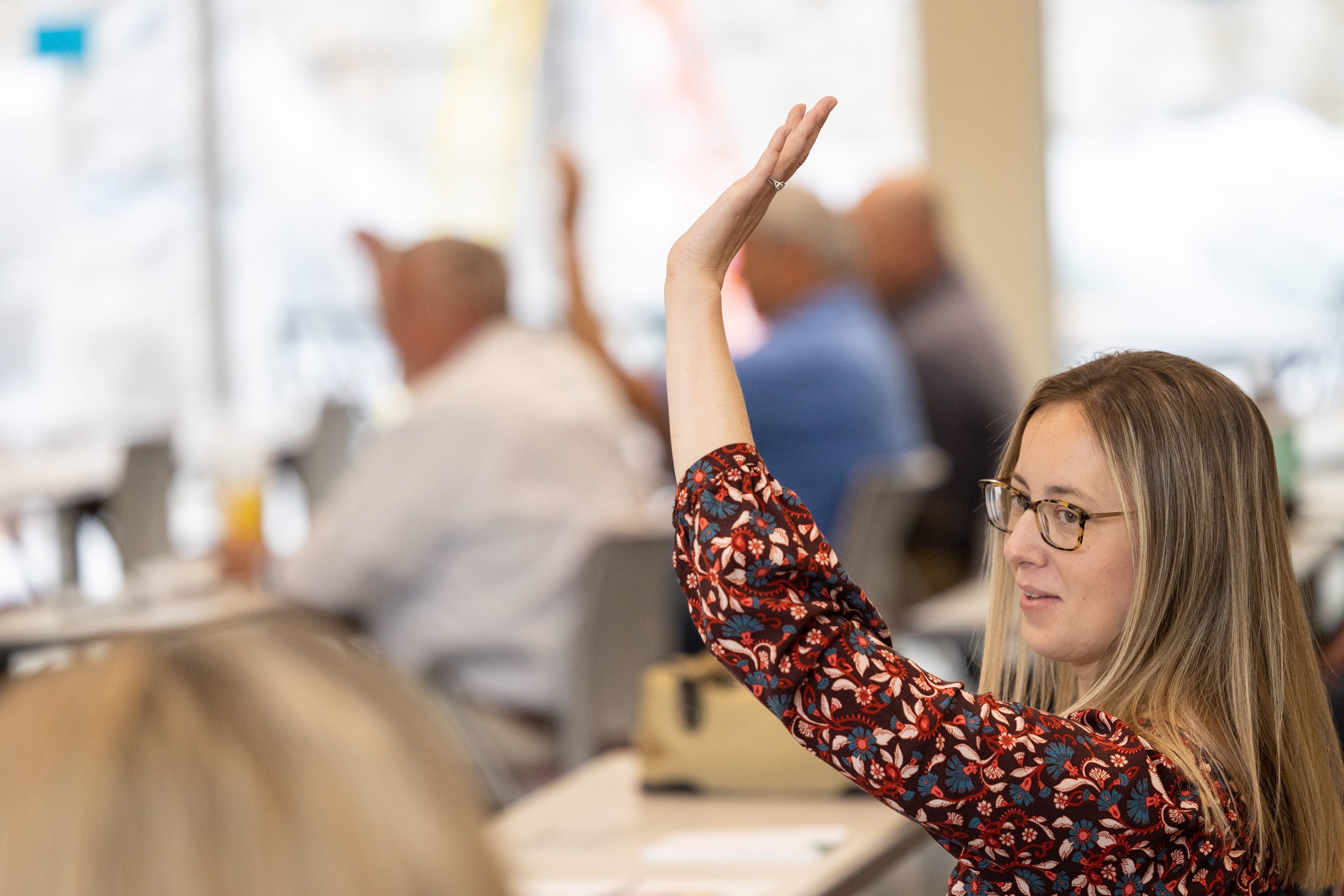 Adult woman raising her hand in a classroom. 